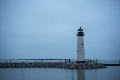 Lighthouse by sea against sky