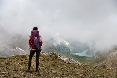 Rear view of man standing on mountain against sky