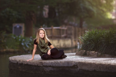 Young woman sitting on retaining wall