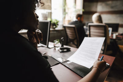 Female lawyer reading contract at desk in law office