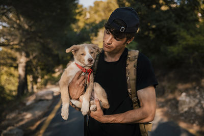 Full length of man holding dog against trees