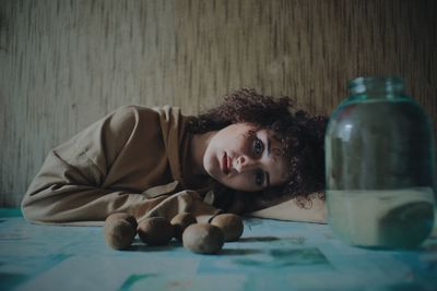 Portrait of woman by fruits and container on table