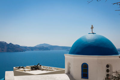 Church by sea against clear blue sky