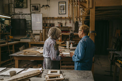 Senior craftswomen discussing together while working at repair shop