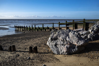 Wooden posts on beach against sky