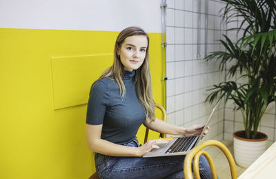 Portrait of confident young woman using laptop in office