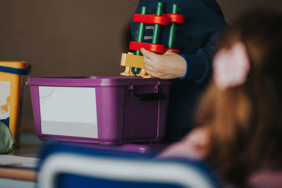 Midsection of boy holding toy in classroom