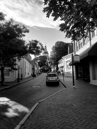 Cars on city street by buildings against sky