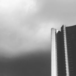 Low angle view of skyscrapers against cloudy sky during foggy weather
