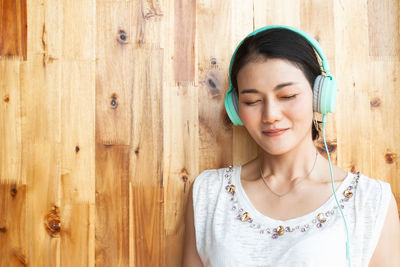 Portrait of beautiful young woman against wooden wall