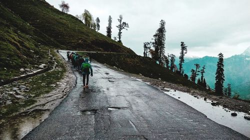 Rear view of person walking on road against sky