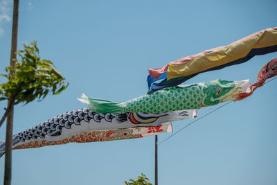 Low angle view of multi colored umbrellas against clear blue sky