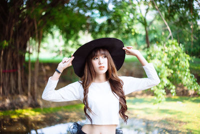 Young woman standing against trees