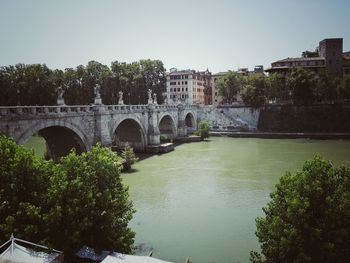 Arch bridge over river against clear sky