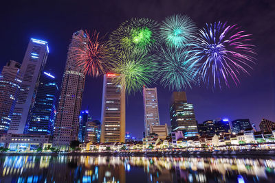 Firework display over illuminated buildings in city at night