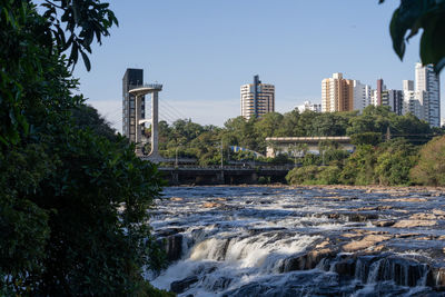 Bridge over river in city against sky