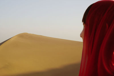 Woman looking at sand dune against clear sky