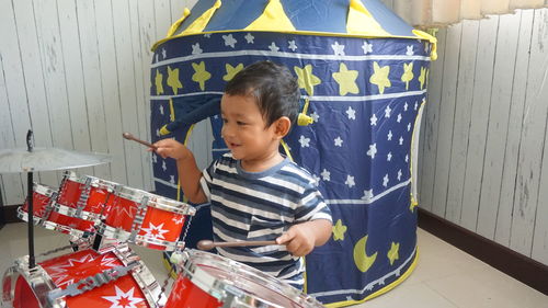 Cute boy playing drums at home