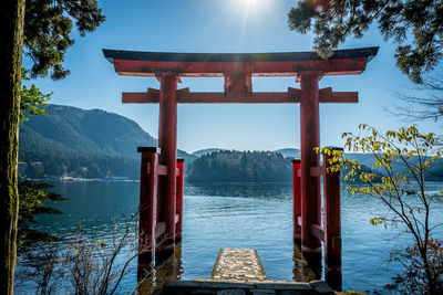Torii gate by lake against sky