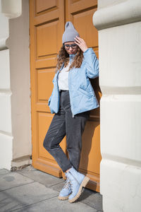 Side view of young woman standing against wall