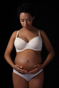 Beautiful young woman standing against black background