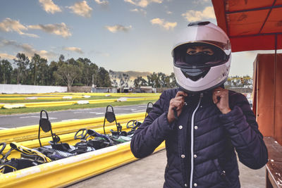 Portrait of adult woman holding helmet in go kart car.