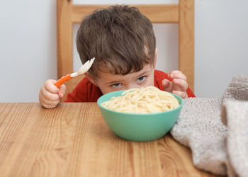 Cute boy is playing with his pasta at lunch time