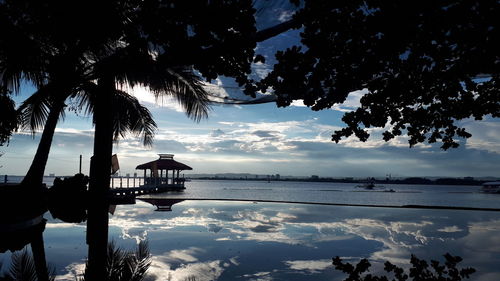Silhouette trees by sea against sky during sunset