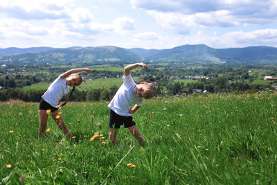 Rear view of boys on field against sky