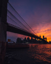 Suspension bridge over river at sunset