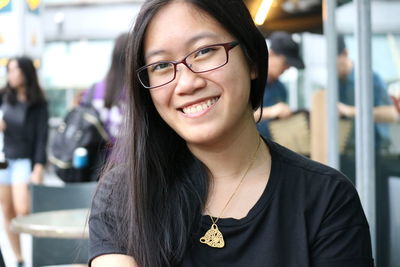 Close-up portrait of smiling woman at sidewalk cafe