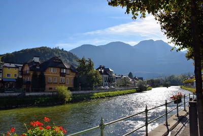 Scenic view of river by buildings and mountains against sky