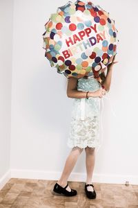 Low section of woman standing on multi colored umbrella