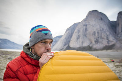 Climber blowing up air mattress while camping in mountains.
