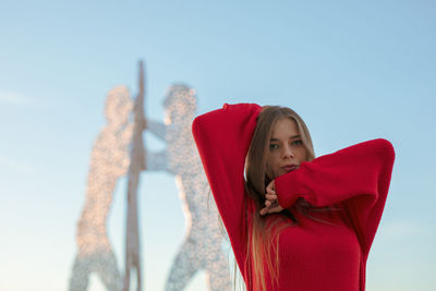 Portrait of young woman standing against clear sky
