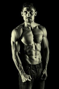 Portrait of shirtless man against black background