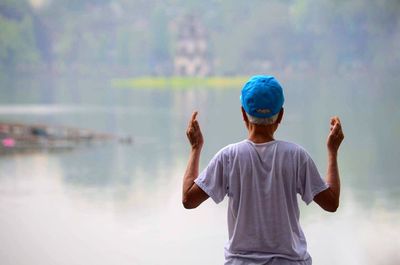 Rear view of man meditating against lake