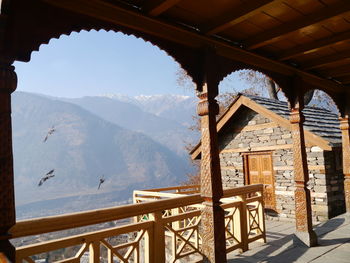 Birds flying against mountains seen though arch of naggar castle