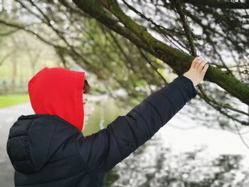 Portrait of boy reaching up to a tree branch 