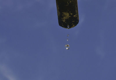 Close-up of drop falling on blue sky