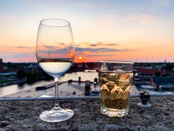 Close-up of beer glass against sky during sunset