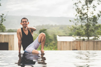 Portrait of young man sitting in swimming pool