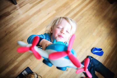 High angle view of boy playing with toy airplane on hardwood floor at home
