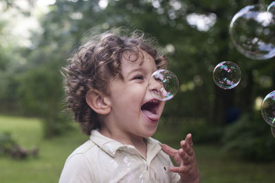 Boy playing with bubbles at park