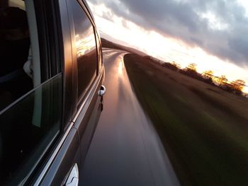 Car moving on road against sky during sunset