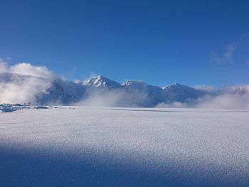 Scenic view of snow mountains against blue sky