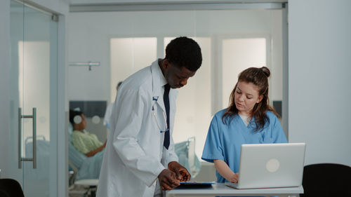 Doctor showing file folder to nurse at desk