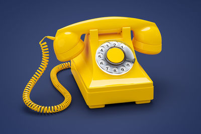 Close-up of yellow telephone on blue background