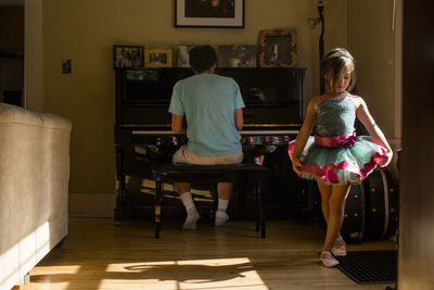 Rear view of girl standing on floor at home