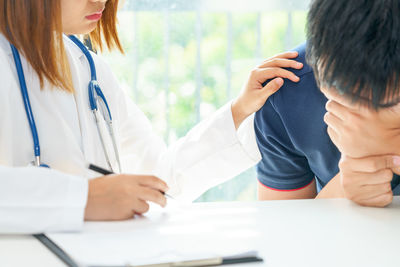 Midsection of doctor consoling patient in hospital